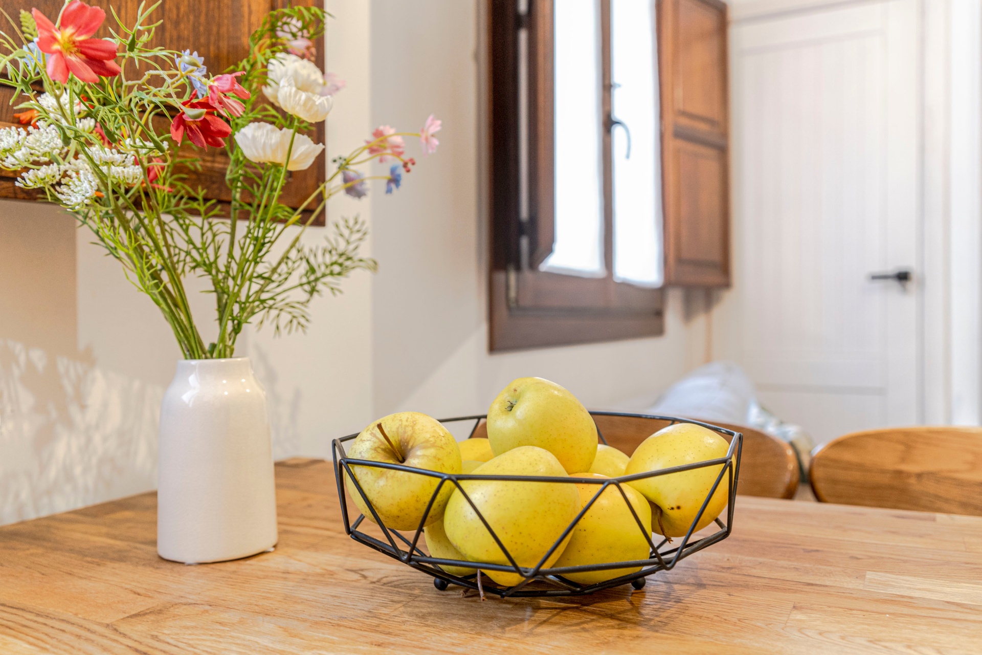 Detalle: frutero y flores silvestres sobre mesa de madera